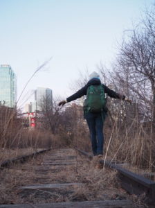 Someone (Katrina) walking with back to camera balanced on an abandoned, overgrown track in winter